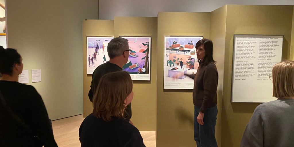 Fem Bouvet designere står foran plakater i museet og diskuterer installasjonen "En orkestrert opplevelse" - som representere tjenestedesign.
