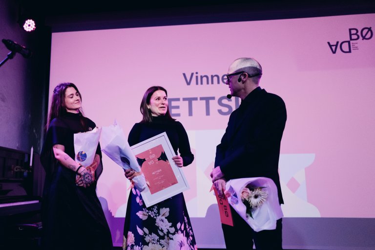 Bilde av vinnerlaget (Emily, Rita og Ole-Henrik)  på scenen med blomst og trofe 