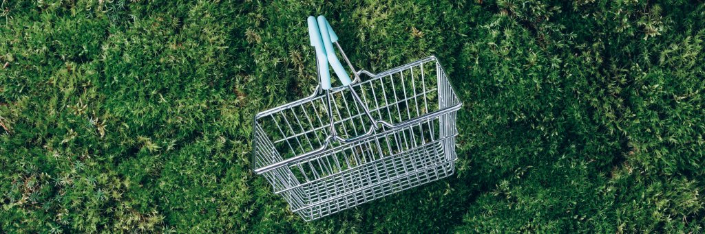 Sustainable lifestyle. Top view of supermarket shopping basket on green grass, moss background. Black friday sale, discount, shopaholism, ecology concept. Sustainable lifestyle, conscious consumption.